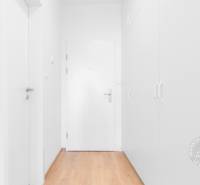 Fehér előszoba szekrénnyel és fa dekorációjú padlóval egy kétszobás lakásban.