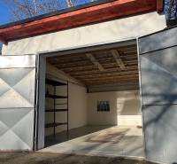 Nyitott garázs az Agátová utcában, Pozsony-Dúbravkán, egyszerű belső térrel és polccal.