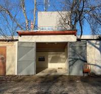 Garázs az Agátová utcában, Pozsony-Dúbravkán, fém ajtókkal és egy székkel kint.