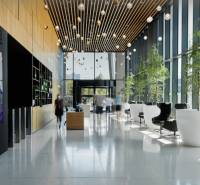 Recepció üvegfalú irodában, növényekkel és kényelmes ülőhelyekkel.