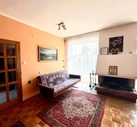 Nappali egy családi házban kandallóval, kanapéval és fa dekorációjú padlóval.