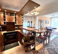 Családi ház belső tere konyhabútorral, étkezőasztallal és fa dekorációjú padlóval.