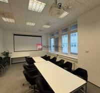 Konferenciaterem az irodákban projektorral, asztalokkal és székekkel, találkozókra előkészítve.