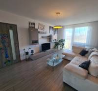 Nappali egy kétszobás lakásban, fa mintázatú padlóval és tágas kanapéval.