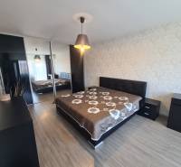 Hálószoba egy kétszobás lakásban nagy ággyal és fa dekorációjú padlóval.