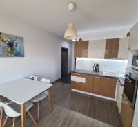 Konyha egy kétszobás lakásban fa dekorációjú padlóval és étkezőasztallal.