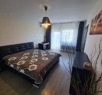 Hálószoba egy kétszobás lakásban ággyal, szekrénnyel és fa dekorációjú padlóval.