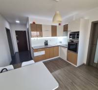 Konyha háztartási gépekkel és asztallal, fa dekor padlóval a kétszobás lakásban.