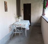 Fedett terasz családi házban, asztal székkel, váza virágokkal, lakótér.