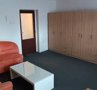 Nappali családi házban kanapéval, asztallal és méretre szabott szekrénnyel.