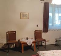 Szoba családi házban fa mennyezettel, két székkel és egy asztallal.