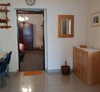 Családi ház belső tere járólappal, fa komóddal és mennyezeti ventilátorral.