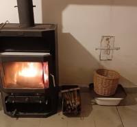 Cserépkályha egy családi házban, mellette kosarak fával és gyümölccsel.