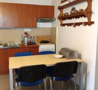 Ebédlő egy családi házban konyhabútorral, asztallal és fali polccal.