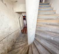 A családi ház belsejébe vezető lépcső, amelynek falain kopott vakolat van.