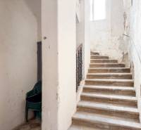 Családi ház lépcsője műanyag székek halmával. Kopott falak.