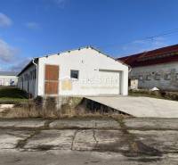 Raktárak és csarnokok külső része Rybkyben fehér homlokzattal és faajtókkal.