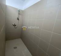 Zuhanyzó bézs csempékkel egy ipari csarnokban.