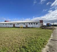 Raktárak és csarnokok Rybkyben, amelyeket zöld terület és betonút vesz körül.