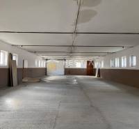 Tágas tér raktárakban és csarnokokban, sor ablakokkal és betonpadlóval.