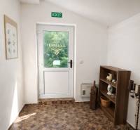 Vendéglátóhely belső terei üvegajtókkal, polccal és fa dekorációjú padlóval.