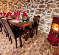 Rusztikus gasztronómiai terek kandallóval, kőfallal és asztalokkal, szalvétákkal.