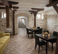 Vendéglátóhely belső terek kőfalakkal és fa dekorációjú padlóval, asztalok virágokkal.