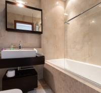 Fürdőszoba káddal és sötét bútorokkal egy kétszobás lakásban, világos csempékkel.