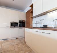 Konyha egy kétszobás lakásban fehér szekrényekkel és készülékekkel.