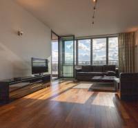 Nappali egy kétszobás lakásban, fa mintázatú padlóval és nagy ablakokkal.