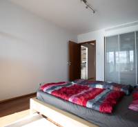 Hálószoba egy kétszobás lakásban, fa dekor padlóval, ággyal és szekrénnyel.