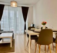 2 szobás lakás fa mintázatú padlóval, étkezőasztallal és kanapéval.