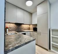 Konyha egy kétszobás lakásban kő munkalappal és fehér szekrényekkel.