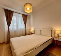 Hálószoba nagy ággyal, függönyökkel és fa dekorációjú padlóval egy kétszobás lakásban.