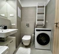 Fürdőszoba egy kétszobás lakásban mosdóval, mosógéppel és WC-vel, modern csempékkel.