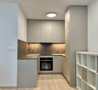 Konyha egy kétszobás lakásban fa hatású padlóval és tároló polcokkal.