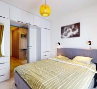 Hálószoba egy háromszobás lakásban kényelmes ággyal, beépített szekrénnyel és fa dekorációjú padlóval.