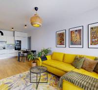 Nappali konyhával egy háromszobás lakásban, sárga kanapé, fa dekoros padló.