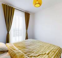 Hálószoba egy háromszobás lakásban ággyal, polcokkal és függönyökkel.