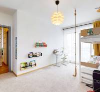 Gyerekszoba egy háromszobás lakásban ággyal, asztallal és gitárral.