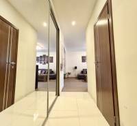 Folyosó egy 2 szobás lakásban csempével, tükörrel és kilátással a nappalira.