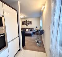 Konyhasarok készülékekkel, bárpulttal és kilátással a nappalira egy kétszobás lakásban.