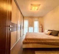 Hálószoba egy kétszobás lakásban nagy ággyal és fa dekorációjú padlóval.