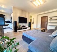 Nappali egy kétszobás lakásban kényelmes kanapéval és fa mintázatú padlóval.