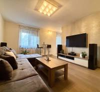 Nappali egy kétszobás lakásban kanapéval és televízióval, fa dekorációjú padlóval.