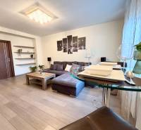 Nappali egy kétszobás lakásban kanapéval, dekorációkkal és fa mintázatú padlóval.