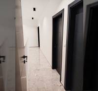 Folyosó egy családi házban csempével és sötét ajtókkal.