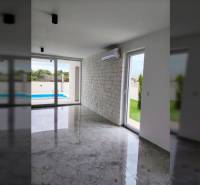 Családi ház belső tere légkondicionálással, nagy ablakokkal és kilátással a medencére.