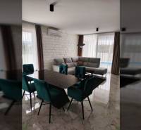 Ebédlő egy családi házban márványpadlóval, étkezőasztallal és szürke kanapéval.