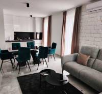 Nappali konyhával családi házban; márvány padló, fehér szekrények, zöld székek.